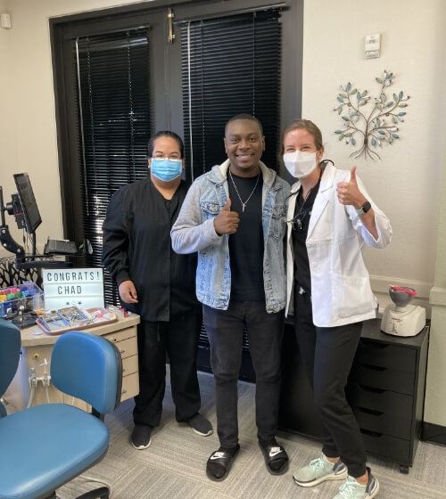 Orthodontists standing with patient who is giving thumbs up