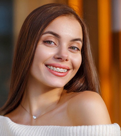 Young woman in cream sweater smiling with braces