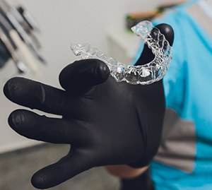 Orthodontist with black glove holding Invisalign in Allen